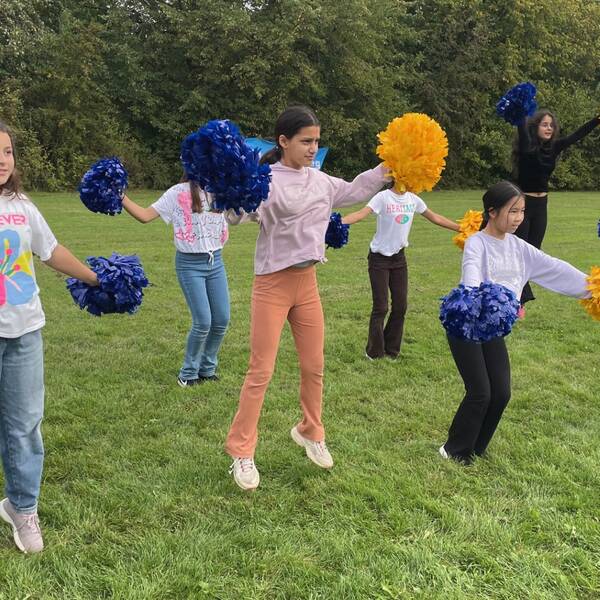 Elever hoppar som cheerleaders på gräsmatta