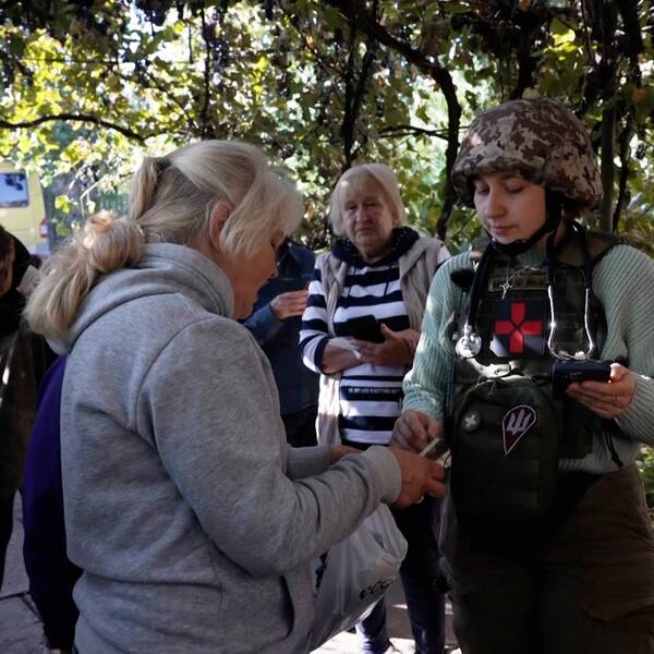 Hjälpvolontären Seema står och pratar med en ukrainsk patient.