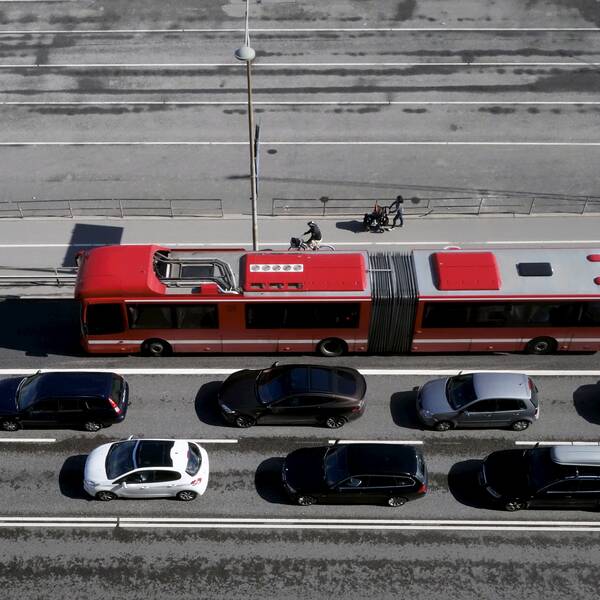 Röd SL-buss åker förbi bilkö.