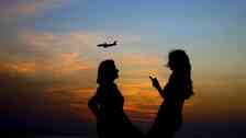 Women share a moment as a passenger plane comes in for a landing at Beirut International Airport while the sun sets behind the Mediterranean Sea in Beirut, Lebanon, Thursday, Nov. 10, 2016. (AP Photo/Hassan Ammar)