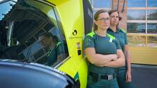 Två kvinnliga ambulanssjuksköterskor står med korsade armar framför en ambulans.
