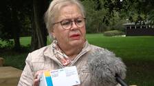 Äldre kvinna med glasögon håller upp diabetesmedicin