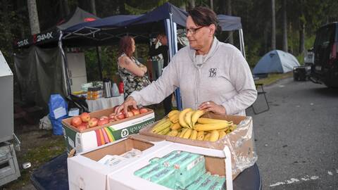 Kvinna står och gör i ordning lådor med frukt.