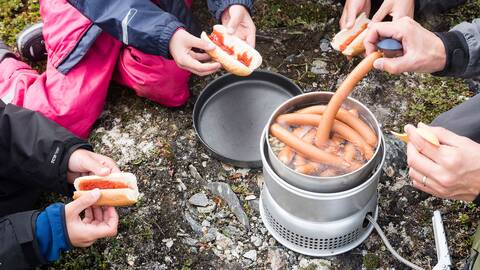 Familj värmer korv på stormkök