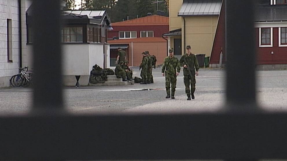 Två militärer går mot grind i förgrunden