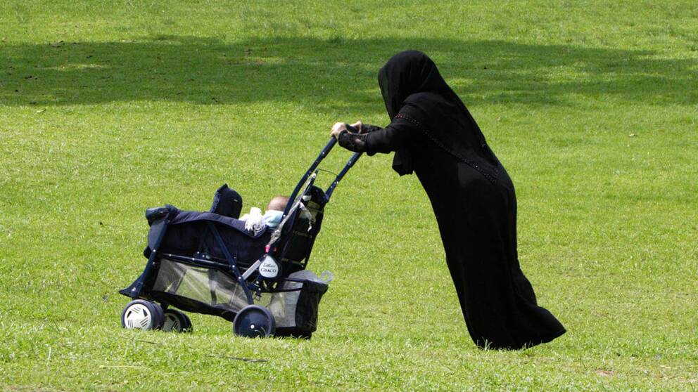 En kvinna med burka och barnvagn