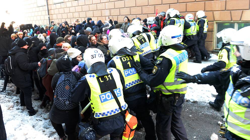 Motdemonstranter hålls på avstånd av polisen när Nordiska motståndsrörelsens demonstration går från Kungsträdgården till Mynttorget i Stockholm under lördagen.