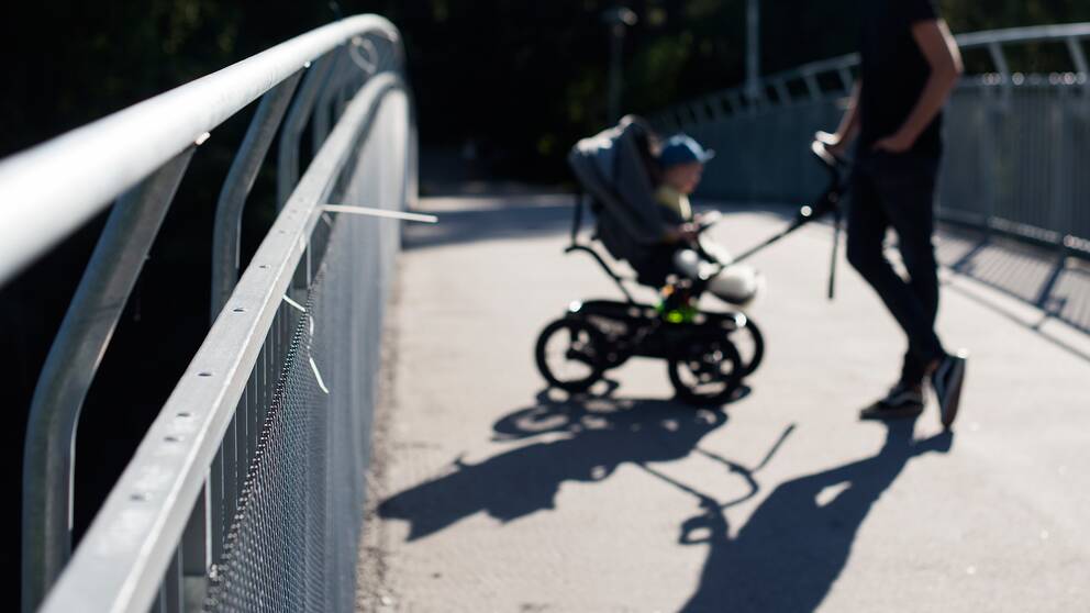 oidentifierbar man med barn i vagn på gångbro