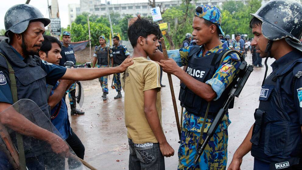 Textilarbetare i Bangladesh grips av polisen. Bilden är från sommaren 2010.