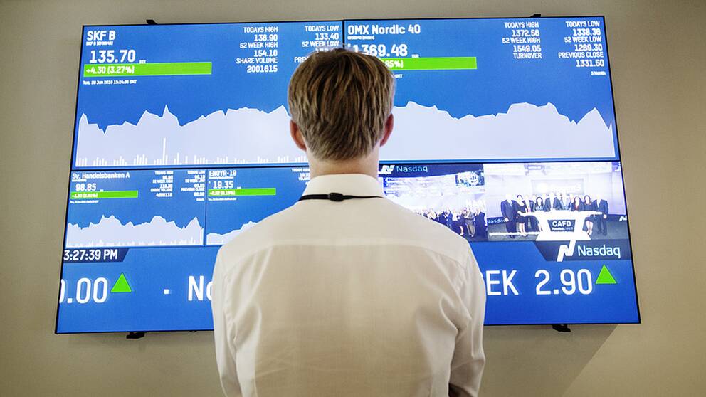 EN man som står framför en skärm som visar börsens utveckling.