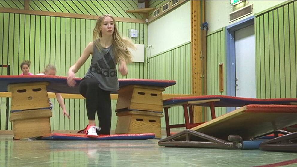 En elev har krupit under ett hinder gjort av plintar och madrasser i en gymnastiksal.