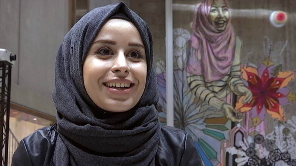 Maram Alawad och hennes porträtt i bakgrunden.