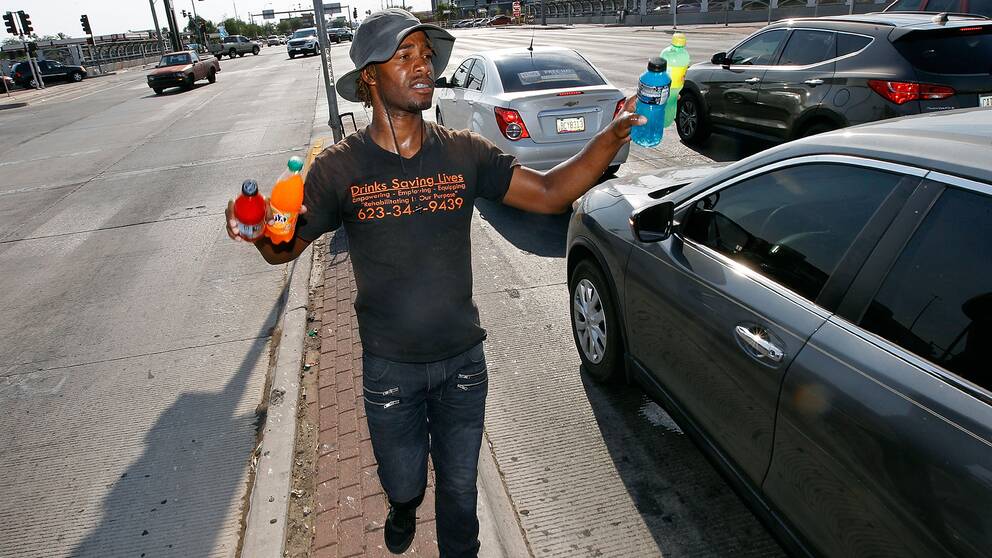 Eric Maurice Clark står mitt i gatan och säljer kalla drycker till bilförare i Phoenix.
