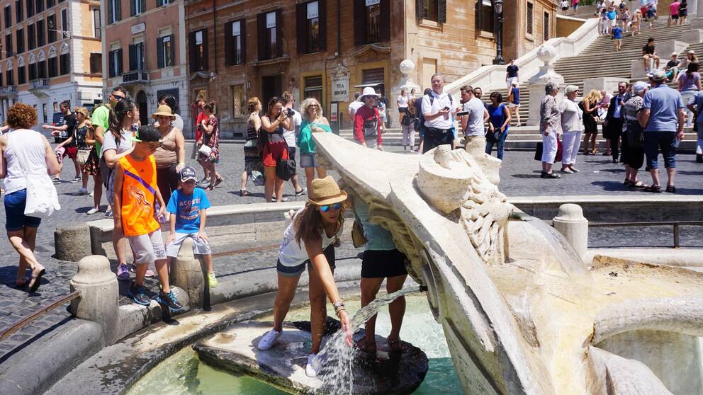 En turist svalkar sig vid fontänen vid Spanska trappan i Rom.