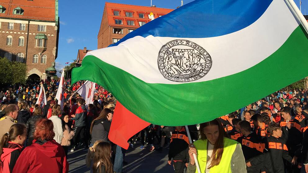massor av folk på torg, Jämtlands-flagga