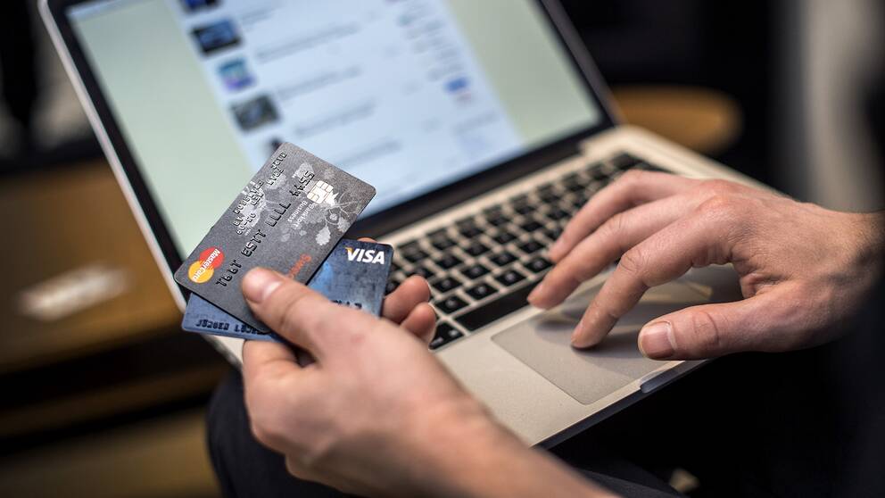 En person sitter vid datorn med kreditkort.