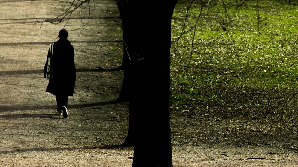 Kvinna promenerar i en park 
