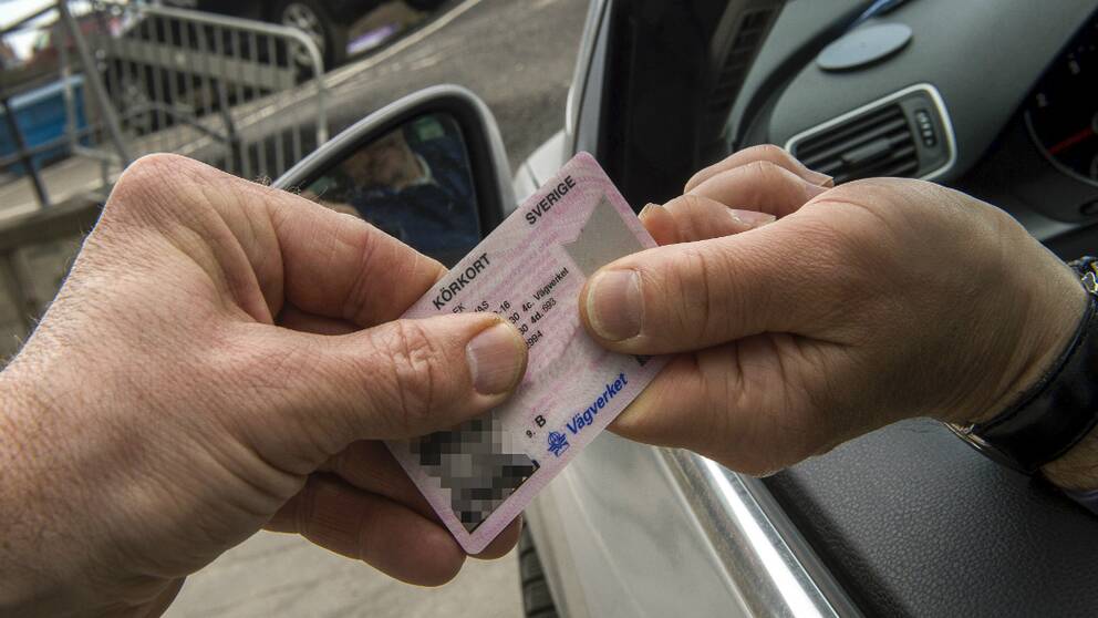 Två händer håller ett körkort.