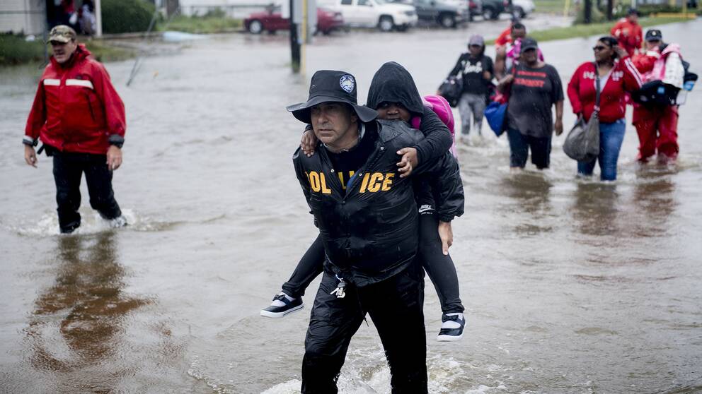 Folk på väg till en luftbåt för att transporteras bort från översvämningen i Houston, Texas.