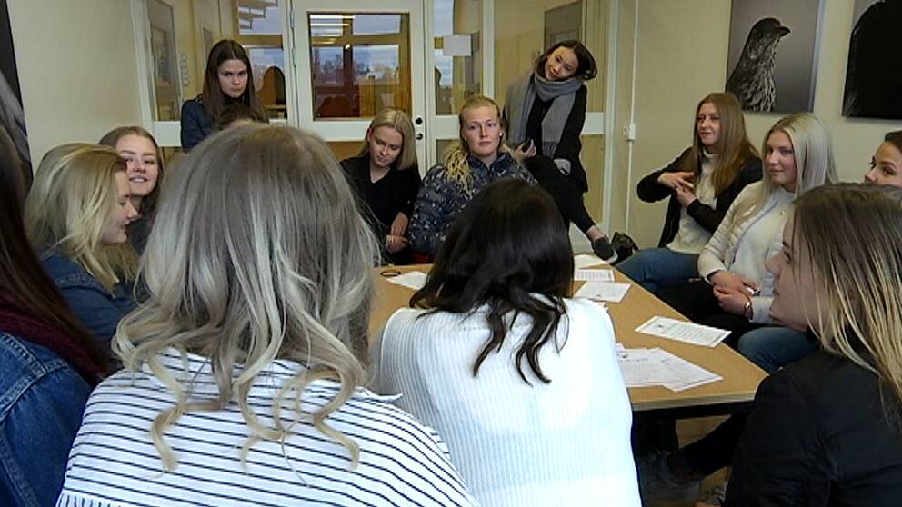 Gymnasieelever, alla tjejer, sitter runt ett bord och pratar med varandra.
