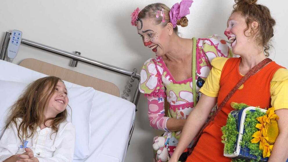  clownerna Gajans och Boel Betula som skrattar tillsammans med flickan i sängen. Fotografen heter Christin Philipson.