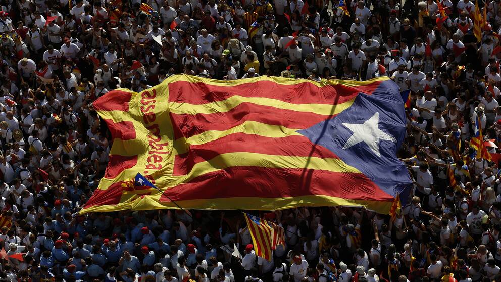 Ett folkhav håller upp en stor katalansk flagga.