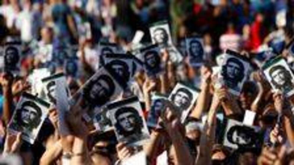 Händer ur en folkmassa håller upp bilder med Che Guevaras ansikte.
