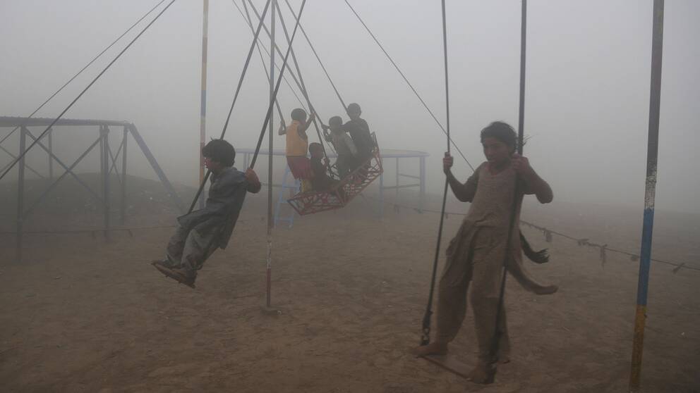 Barn leker på gungor i Lahore i tjock smog.