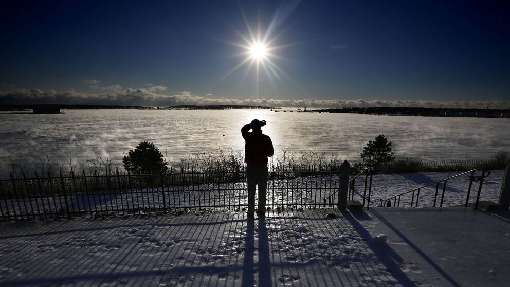En man står och tittar mot solen.