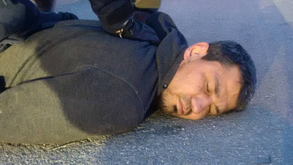 En bild föreställande misstänkte terroristen Rakhmat Akilov liggandes på asfalt med polisers armar över sig.