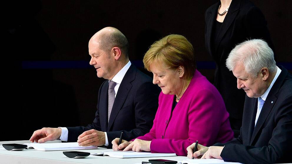 Angela Merkel skriver under regeringsförklaringen med finansminister Olaf Scholz (SPD) till vänster och inrikesminister Horst Seehofer (CSU) till höger.