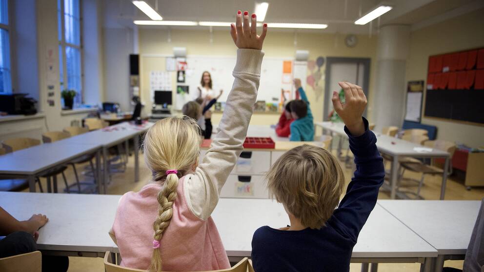 Barn i ett klassrum som räcker upp sin hand.
