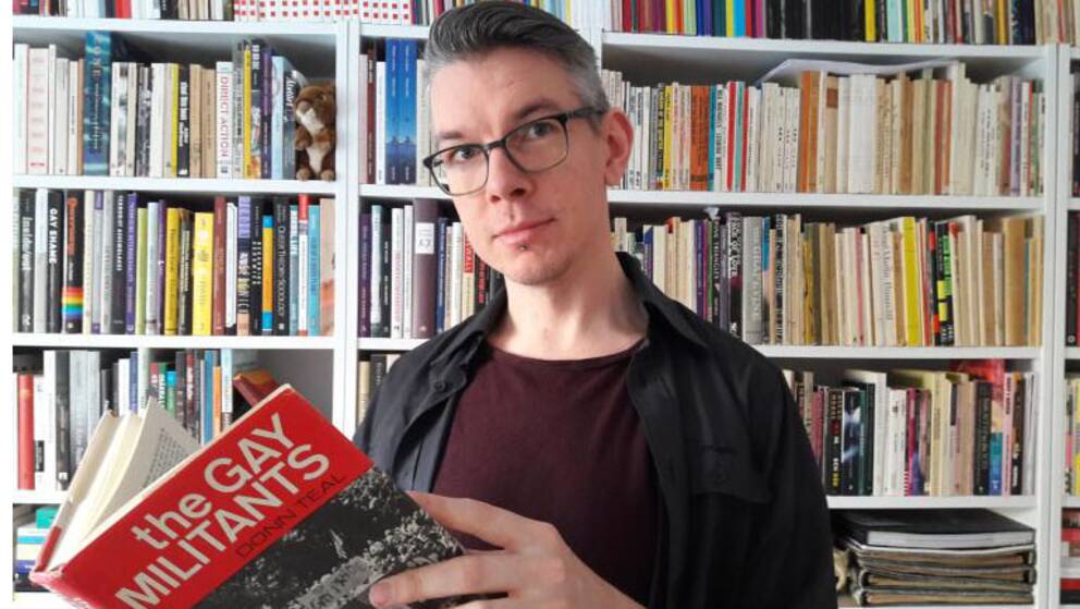 Bibliotekarien Olov Kriström med en av bibliotekets böcker.