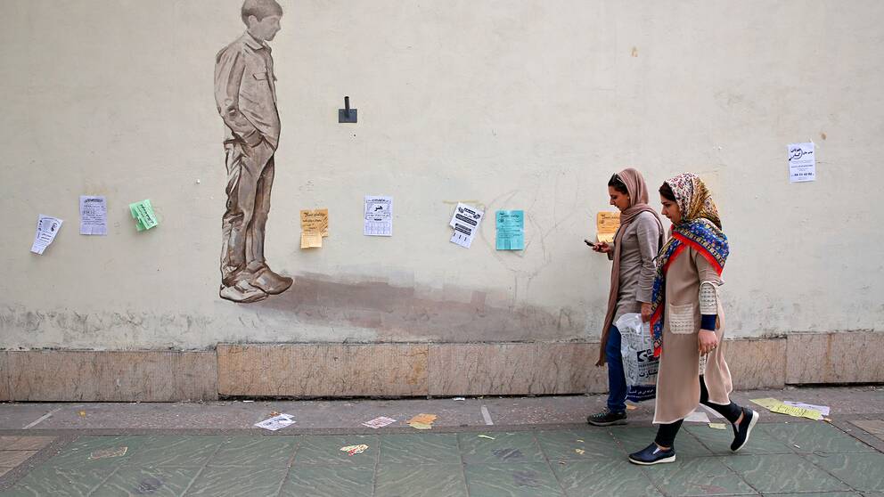 Två kvinnor går på gatan i Irans huvudstad Teheran. 
