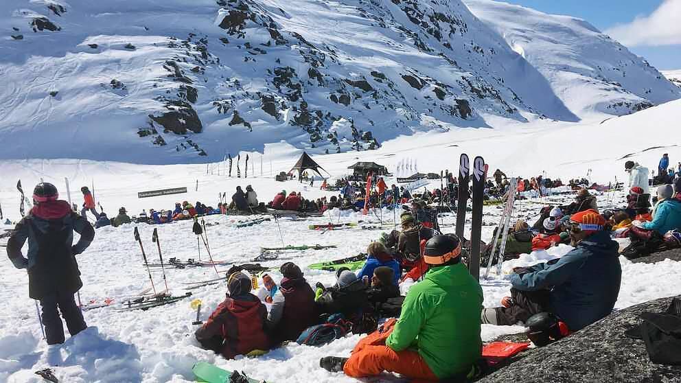 publik sitter i snön nära foten av berg