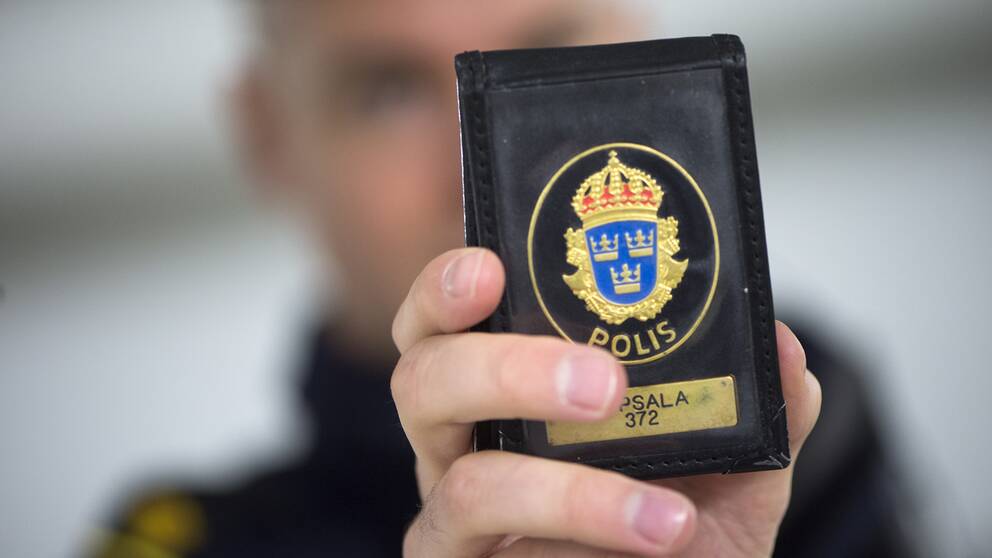 Polis håller upp polisbricka.