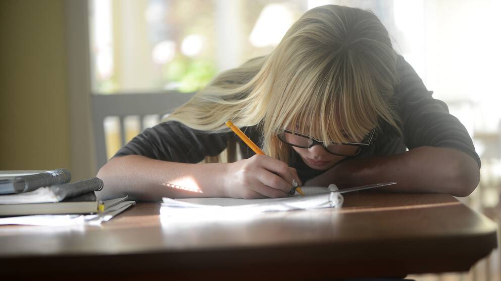 En flicka pluggar skriver en läxa fokuserat vid ett bord