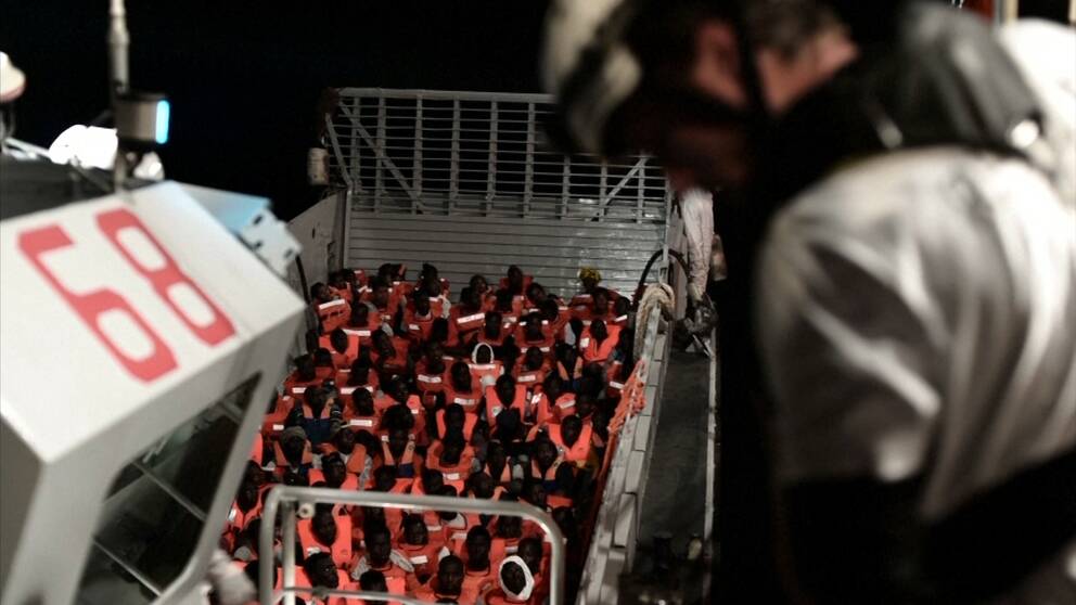 Migranter sitter ned i en båt som befinner sig på Medelhavet.