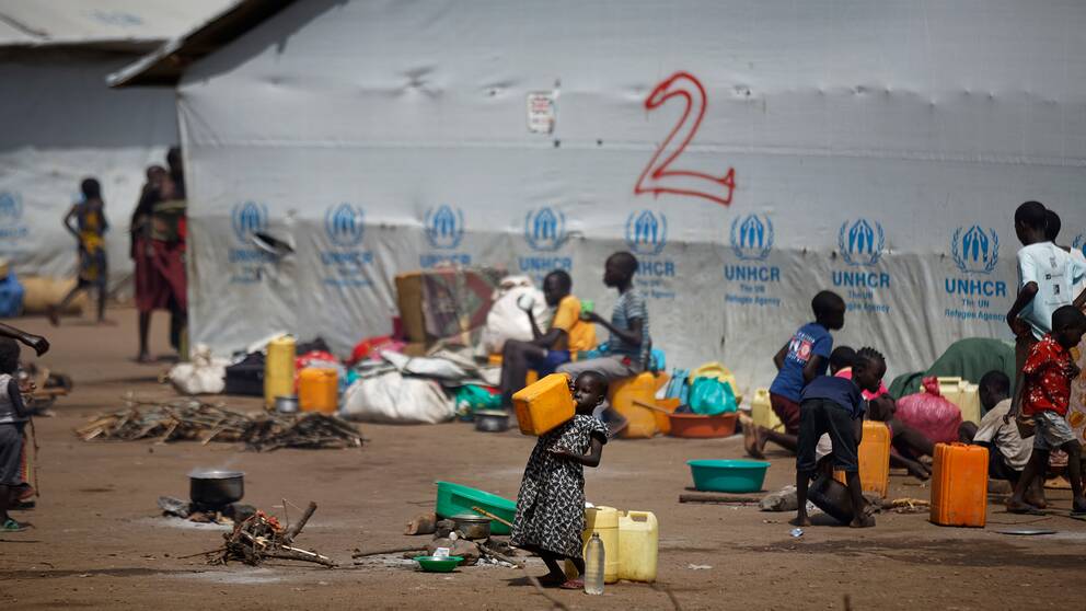 En flicka dricker vatten ur en dunk i ett flyktingläger i norra Uganda.