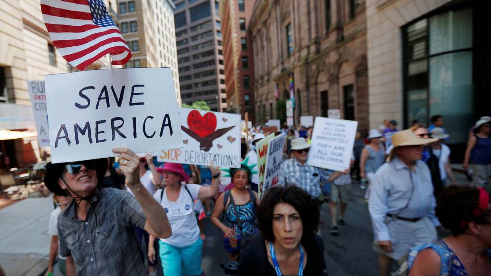 Demonstranter med plakat där det står ”rädda Amerika” och ”stoppa deportationerna”.