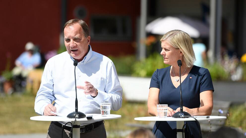 Stefan Löfven  och Magdalena Andersson står vid ett bord och talar.