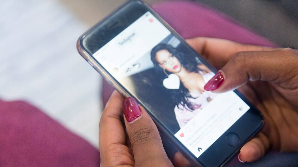 En ung kvinna kollar instagram på mobilen.