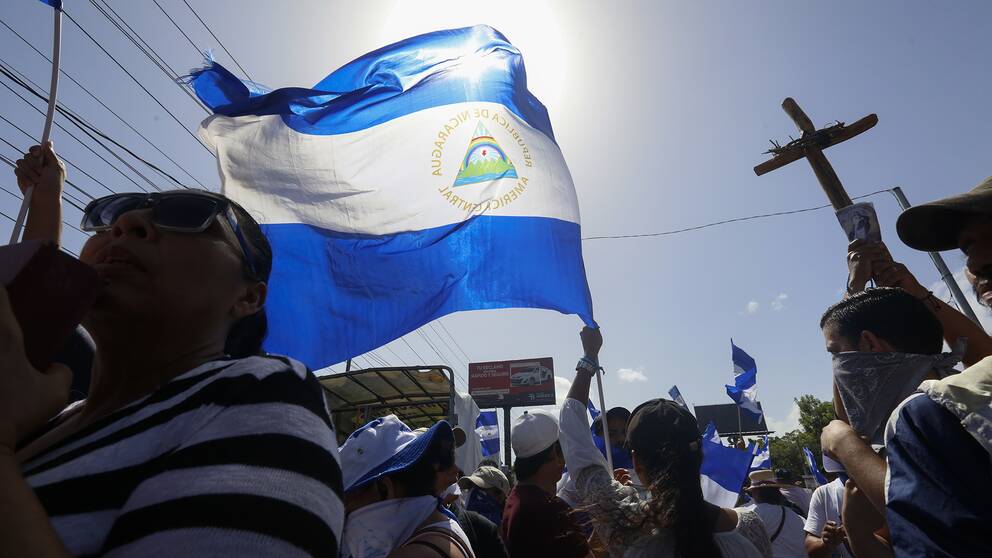 Folk som bär flaggor och kors under demonstration i Managua