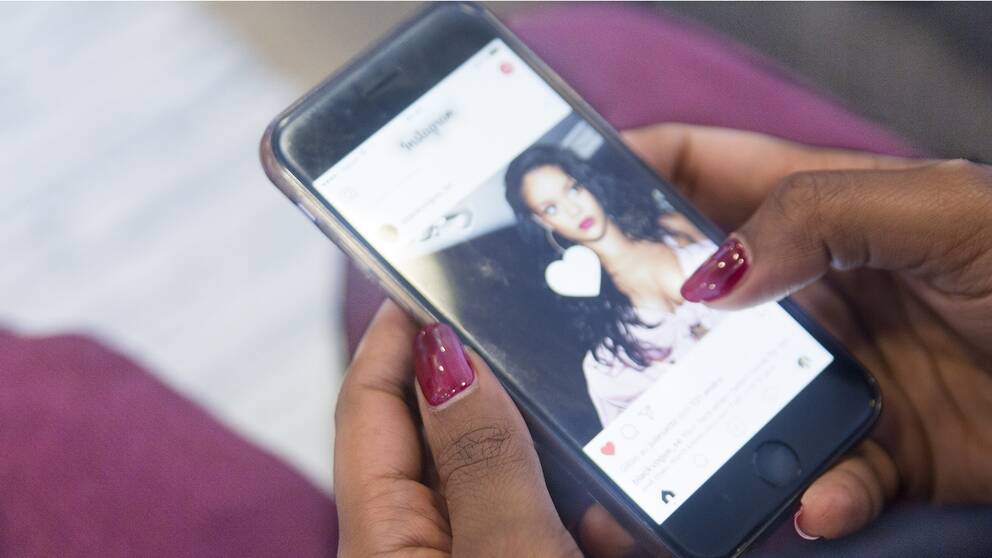 Ung kvinna kollar Instagram på mobilen.