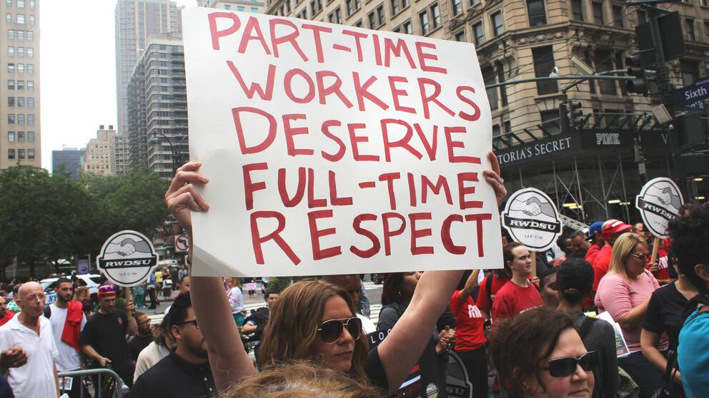 Folk som demonstrerar och bär på ett plakat med texten part-time workers deserve full-time respect