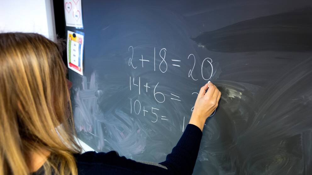 En lärare som räknar matte på tavlan.