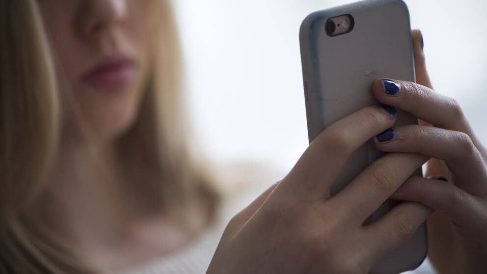 En tonåring med sin mobiltelefon.