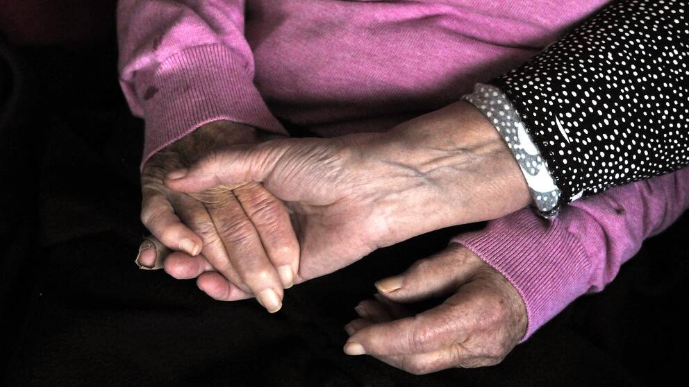 Två äldre kvinnor håller varandra i handen.