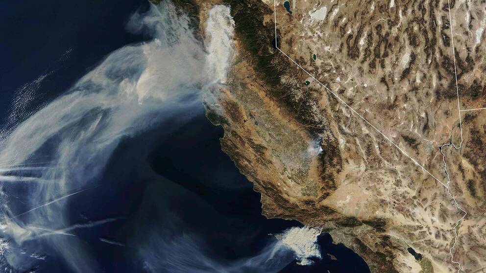 Röken från de stora skogsbränderna i södra och norra Kalifornien sprids hundratals mil ut över Stilla havet av de starka Santa Ana-vindarna.