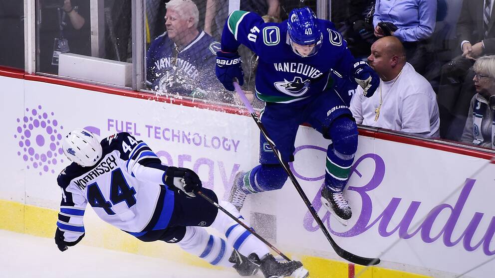 Elias Pettersson, i blått, tacklas av Winnipeg-backen Josh Morrisey.